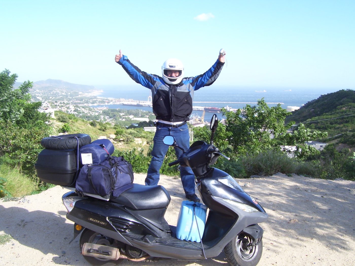 Antonio Rodríguez con los brazos abiertos frente al mar en Salina Cruz, Oaxaca, junto a La Malinche